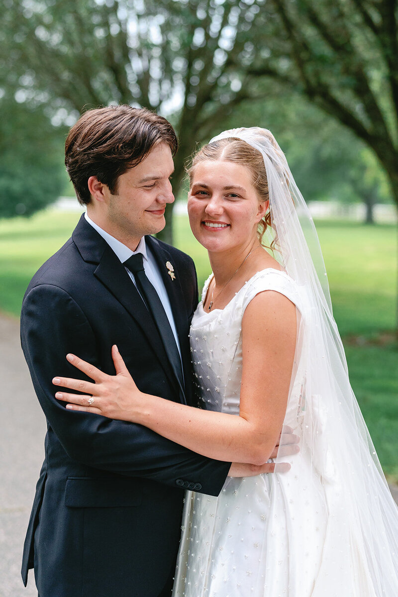 Married couple embracing while the bride smiles at the camera for their Nashville wedding