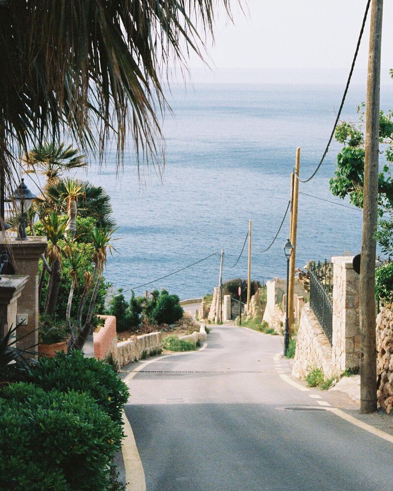 A picture taken from the top of a hill showing a winding road leading to the ocean