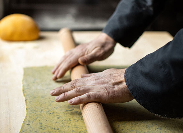 Close-up of a chef rolling fresh dough during a private cooking class in Pesaro, Italy—where guests learn to make traditional Piadina Sfogliata on the Wish You WERE Here Italy Tour with author Christy Schillig.