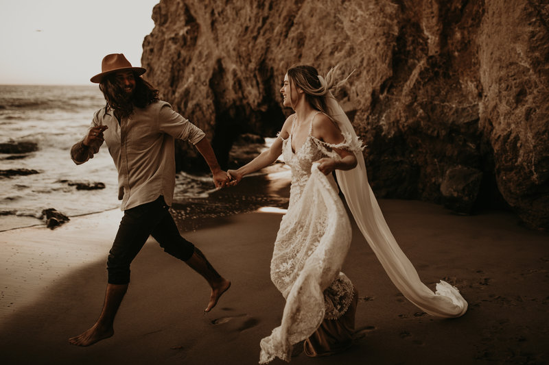 bride and groom walking over rocks