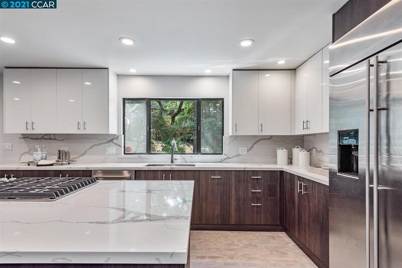 A brightly lit kitchen with dark wood cabinets and white marble countertops