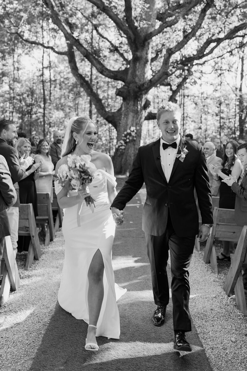 A joyful bride and groom celebrate as they walk down the aisle after their wedding ceremony, filled with love and excitement. Girasole & Co. Weddings, Columbus, Ohio’s expert wedding planner, specializes in designing personalized, seamless weddings that reflect your unique love story. Let us make your special day unforgettable with our expert planning and attention to detail.