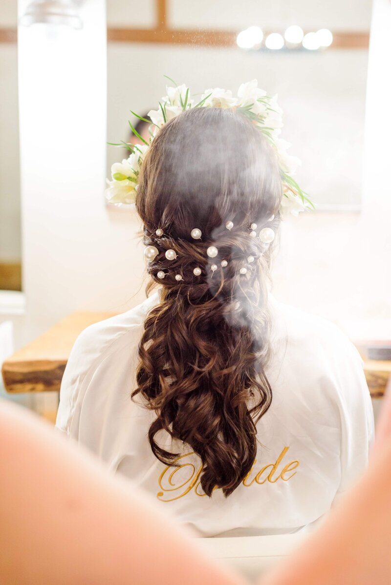 Hairspray is sprayed on the bride's hair in the bridal suite at Camelot Meadows.