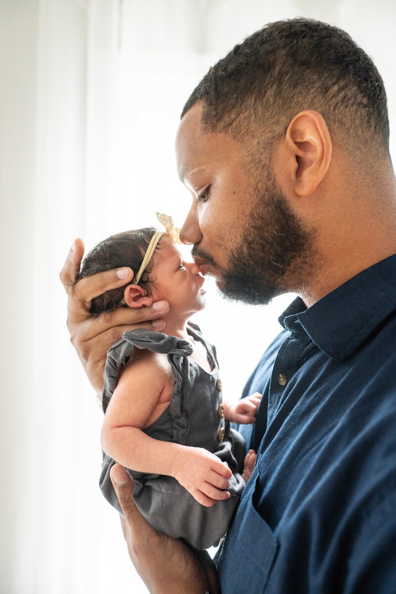 dad kissing her newborn baby girl on the nose