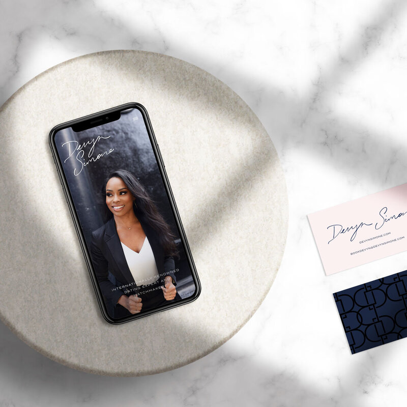 Phone screen of website beside business cards for luxury branding project