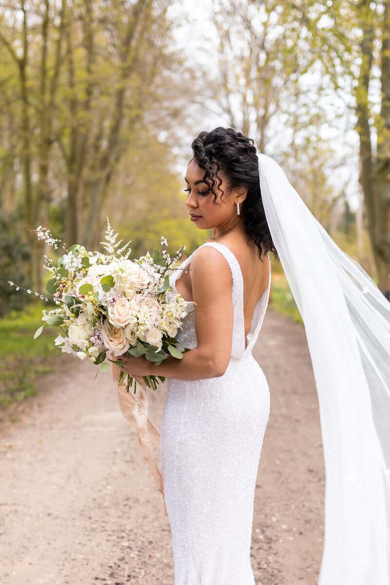 afro bride outside holding bouquet long veil