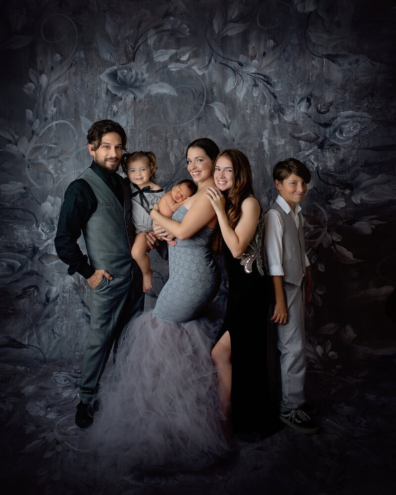 Fine art family portrait of NJ family of 6 on a floral grey background wearing formal attire.