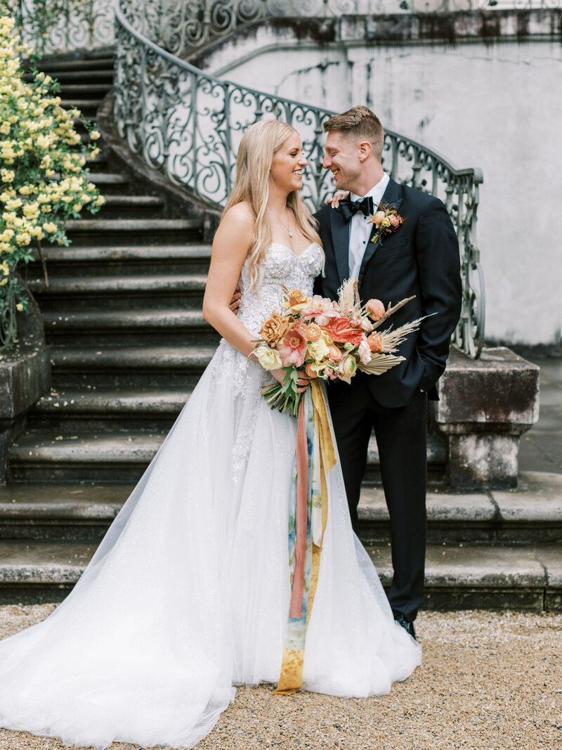 Below the waste close up of bride and groom holding hands and bouquet