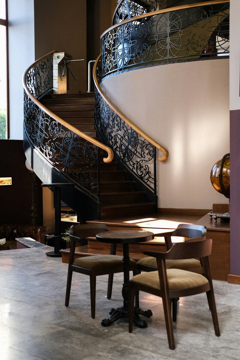 Interior photo of a curved staircase that leads down to a room with a small table and chairs