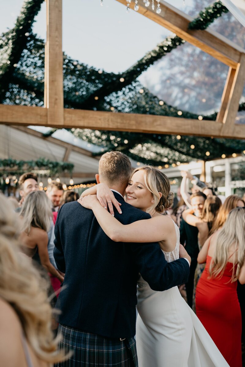 A bride and groom hug on the dancefloor of House of Elrick's wedding barnquee.