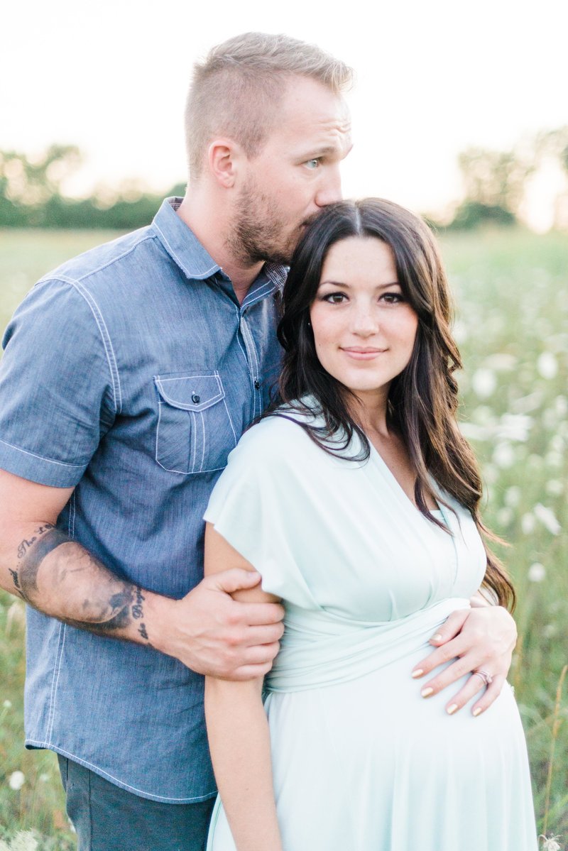 man kissing his pregnant wife on the head