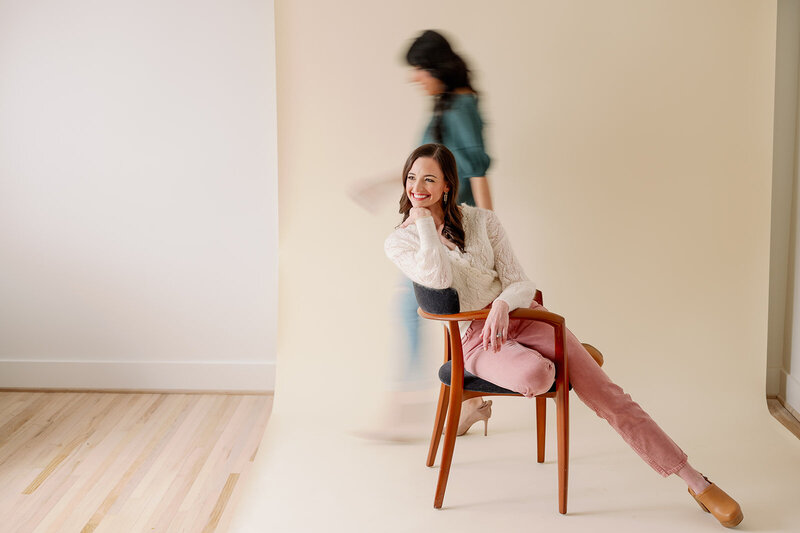 Blurred woman walking behind a woman sitting in a chair