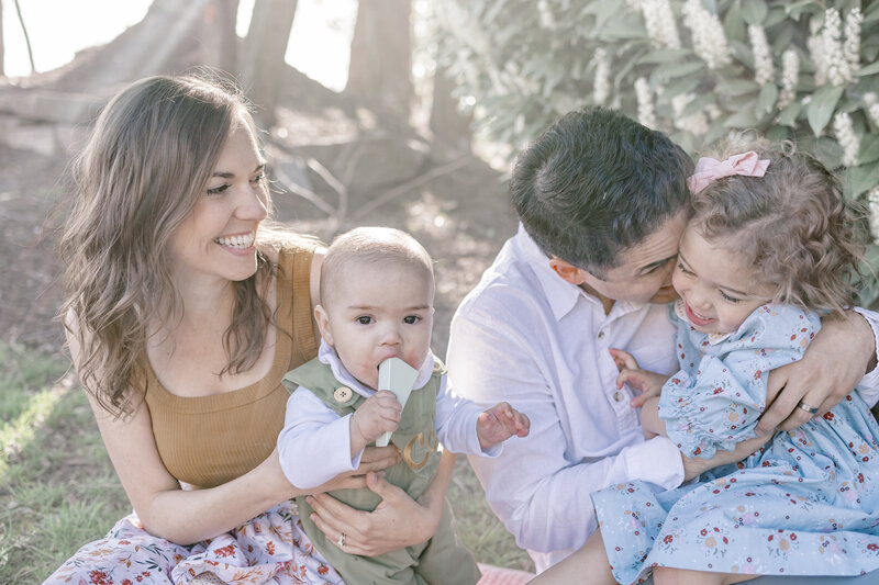 Mother smiling at father and daughter while holding her son