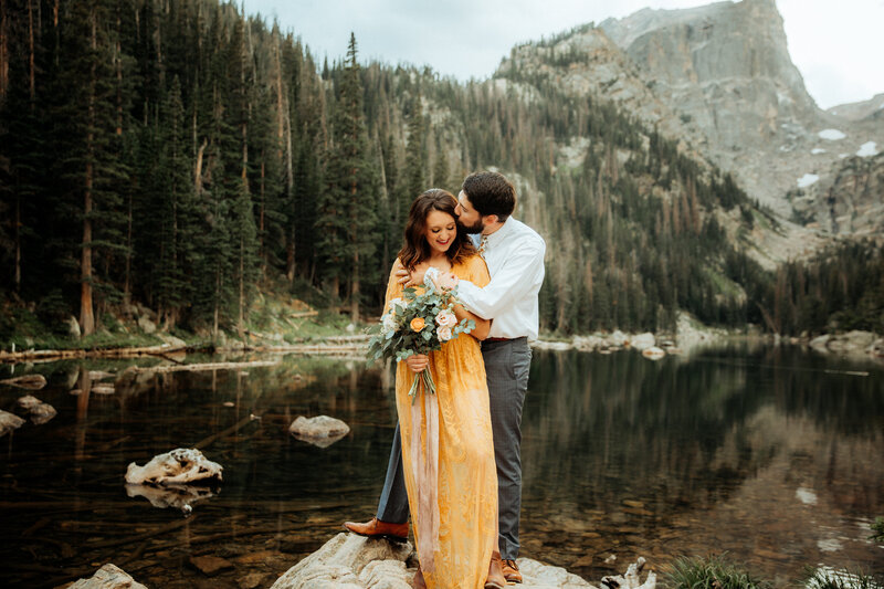bride and groom holding eachother by a lake