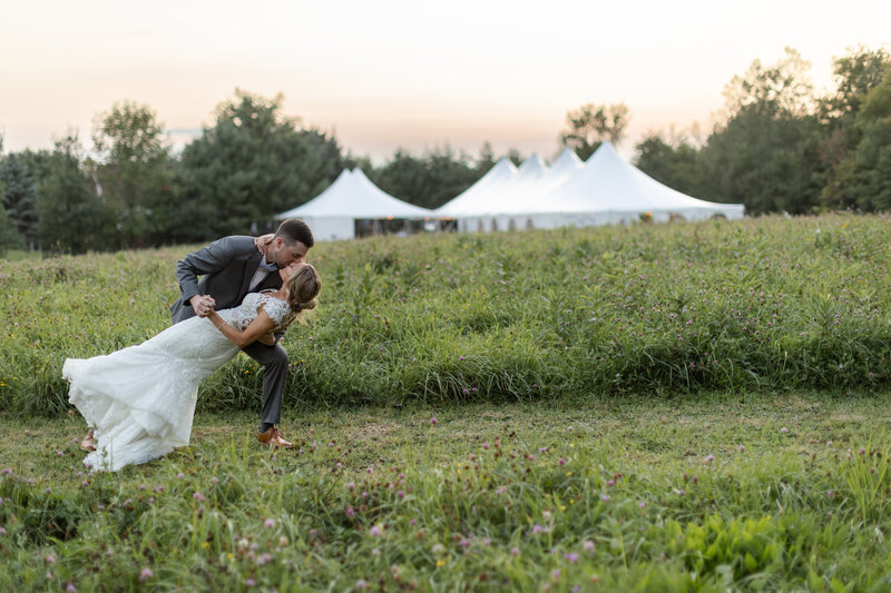 Bride and groom stand under an umbrella while resting their heads together with their eyes closed