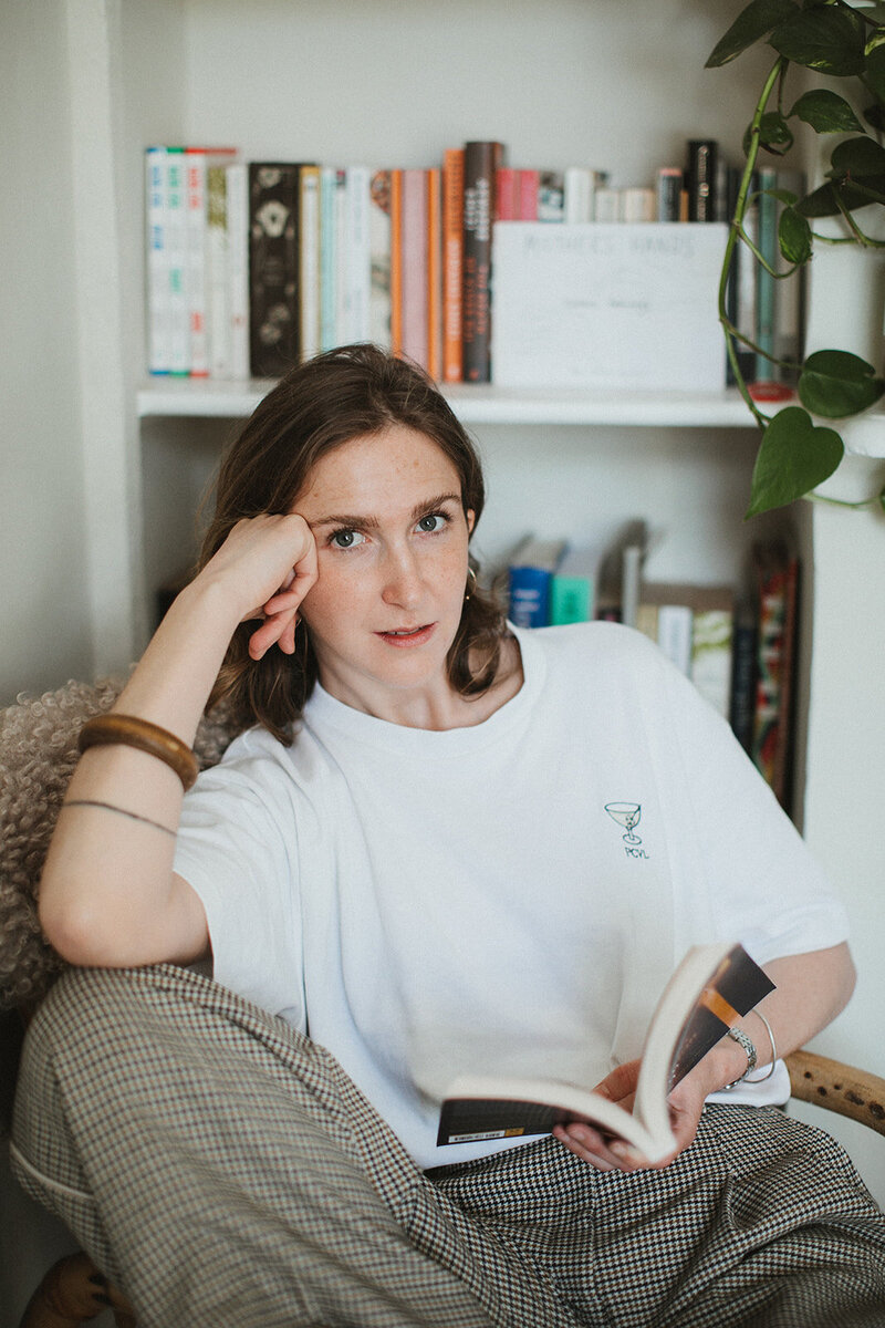 Business coach and mentor looks to camera, taking a pause from reading about women's ambition