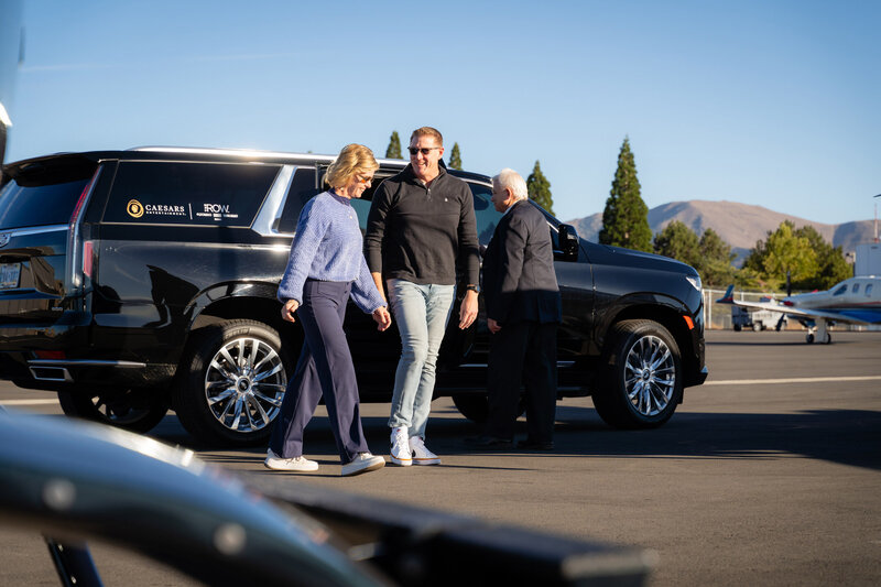 man and woman smiling and standing by black car 