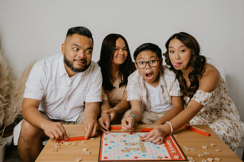 family of four making funny faces while playing scrabble