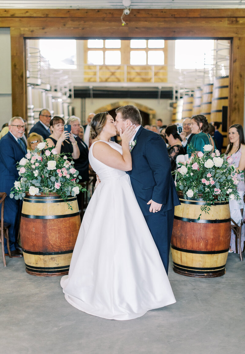 Couple kissing at end of aisle at Stone Tower Winery.