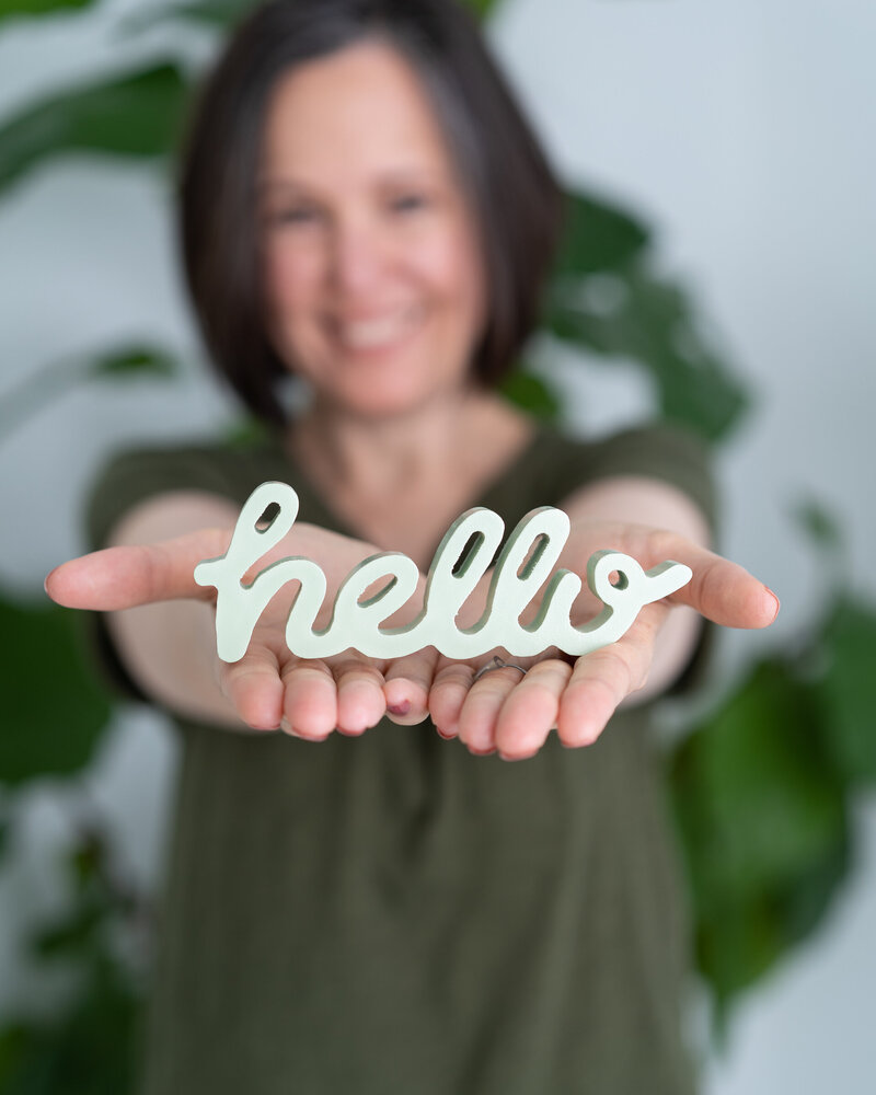 Sacramento photographer of Robin Collette Photography holding  a hello wooden word sign.