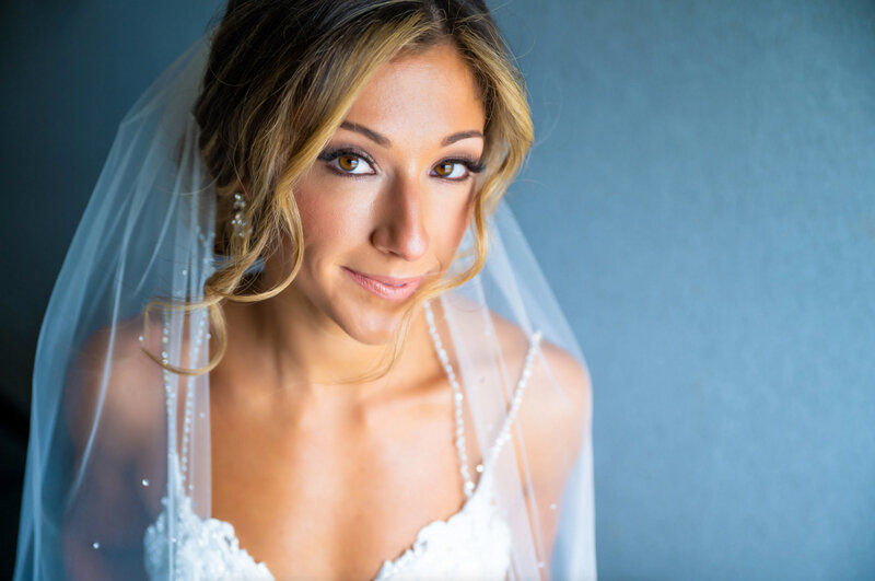 Portrait of a bride with her hair blowing in the wind in front of a blue wall in Mount Laurel, New Jersey