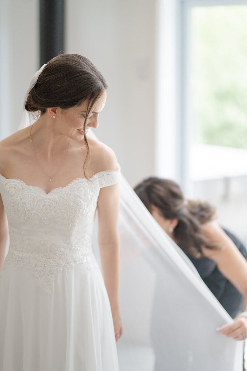 Préparation de la mariée, aidée par sa mère pour ajuster un long voile