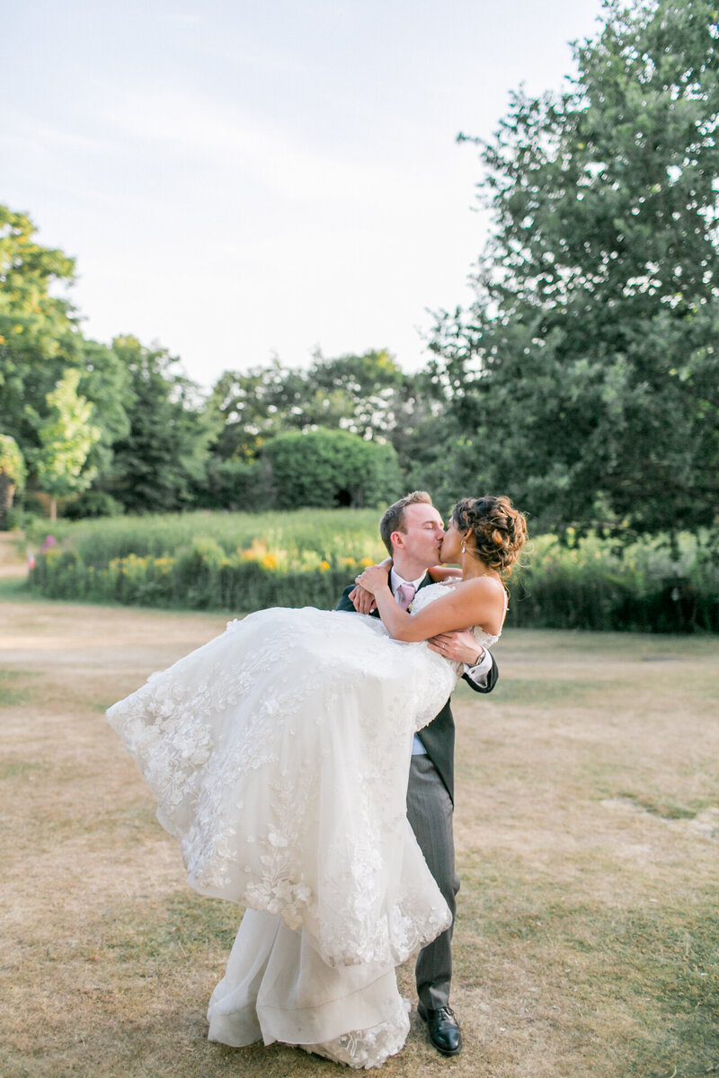 Groom lifting his bride up and having a kiss at their Hampton Court House wedding in Surrey
