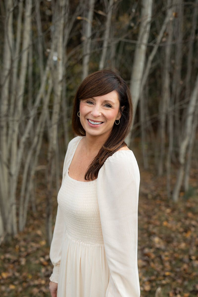 Courtney, family, lifestyle and portrait photographer in Massachusetts, posing with camera in a field.