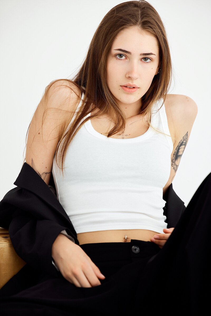 Edgy and fashion-forward personal branding portrait of a confident young woman wearing a white tank top and oversized black blazer, styled for a bold, minimalist look.
