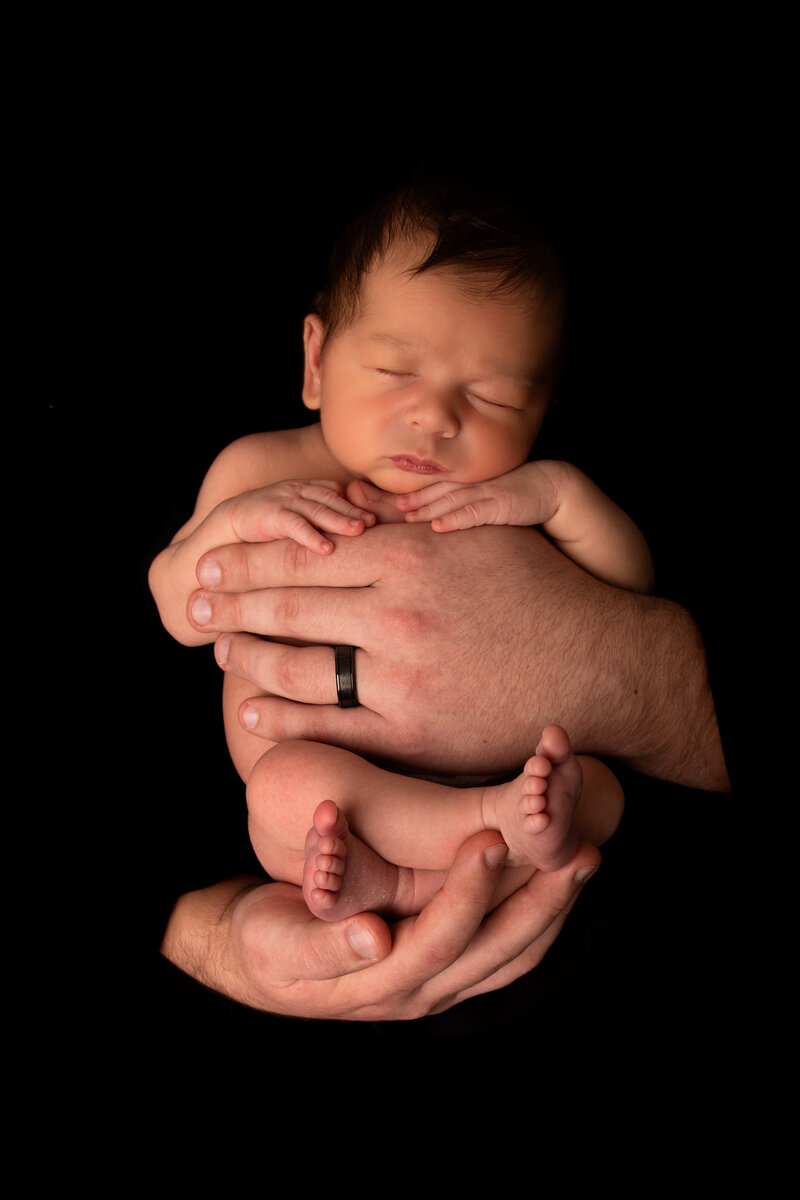 newborn baby held in parents hands
