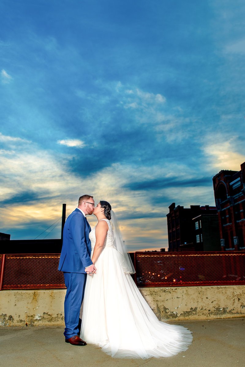 Bride and groom kiss with deep blue sky in background