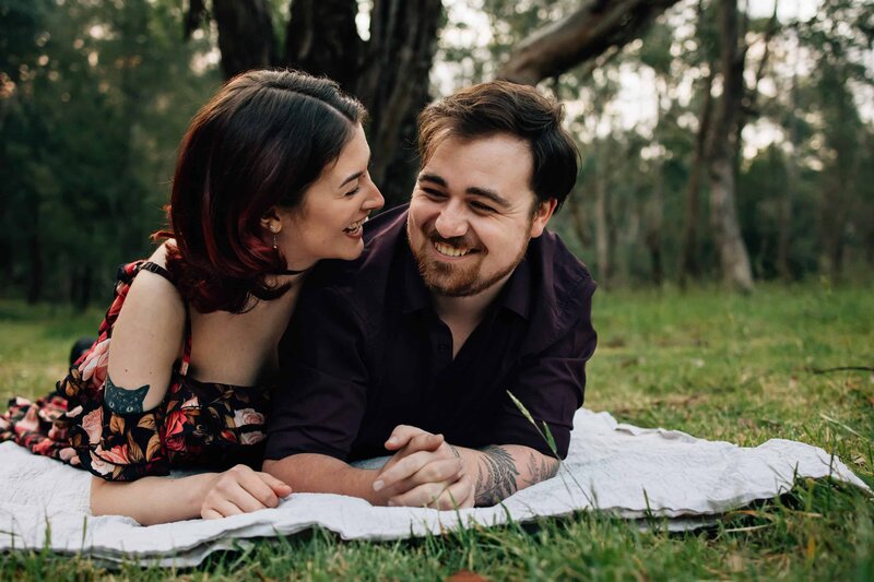 Couple lying down on rug, looking at each other and laughing. Couples photoshoot Melbourne, And So I Don’t Forget Photography