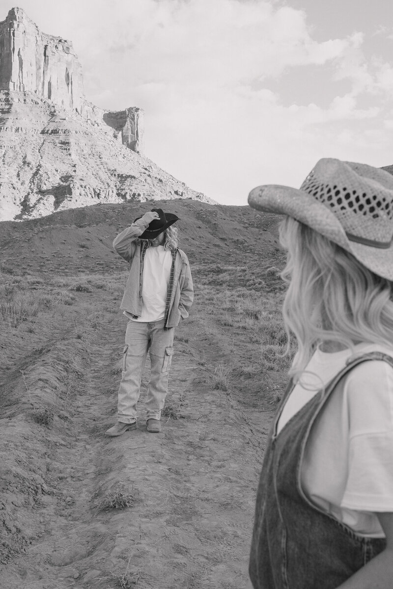 Candid shot of the man holding his hat while his wife looks at him and the views of the desert