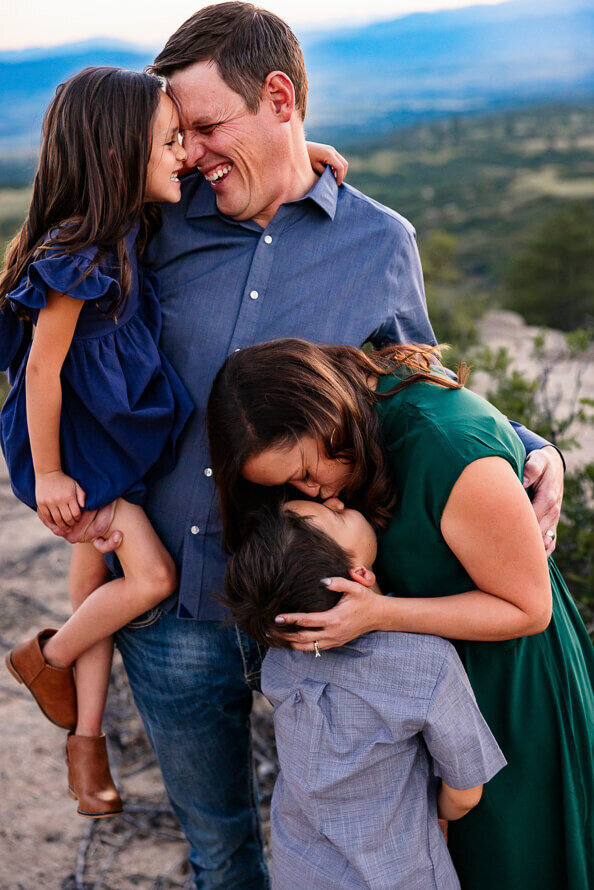 a family of four kiss each other during family photos at Daniels Park on Colorado.