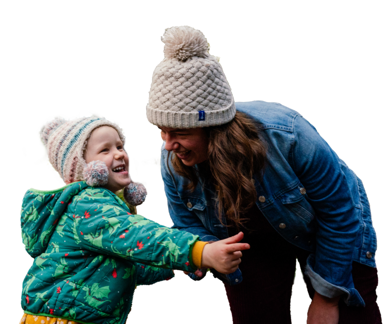 a mum holding her daughters hand looking at her as they both laugh. 