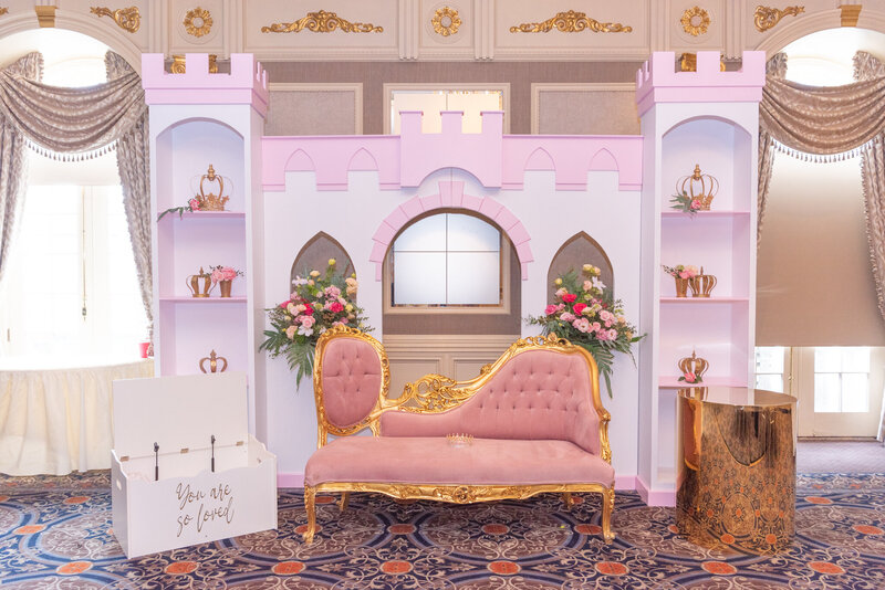 Princess castle theme decoration with a pink royal couch at a baby shower event.