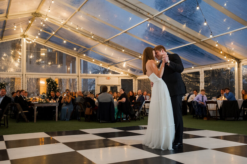 Newlyweds sharing their first dance under a clear tent with string lights during a romantic Austin wedding reception planned with thoughtful care.