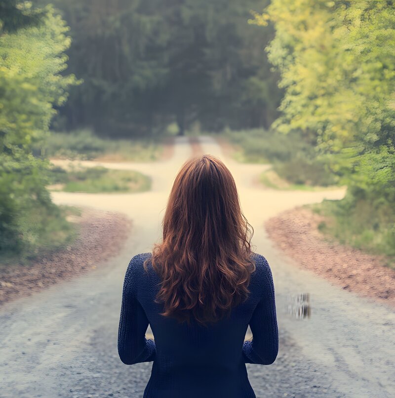 Mujer frente a una bifurcación de caminos en el bosque, representando la toma de decisiones con la ayuda del Código Bíblico.
