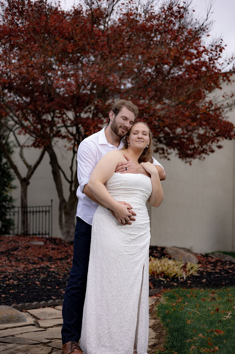 A tender moment between bride and groom under a red maple tree at Our Lady of the Cedars in Fairlawn, Ohio