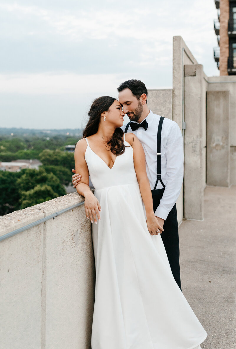 Bride and groom posing against a concrete wall with their heads together