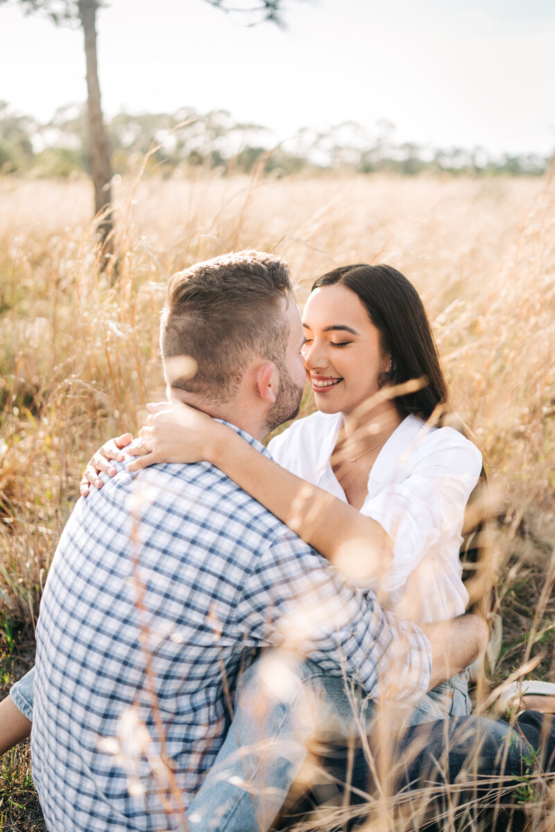 Best Palm beach engagement photographer captures couple sitting down in the middle of a field enjoying eachother