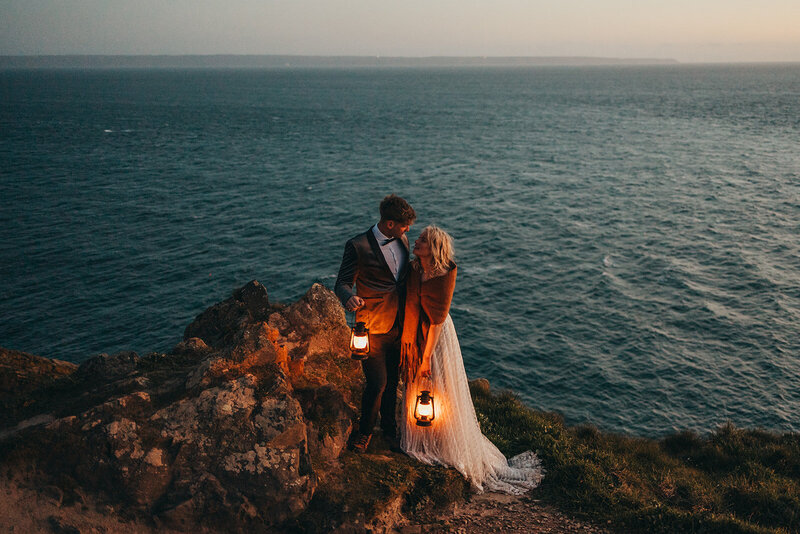 couple pose with lanterns by cliffs