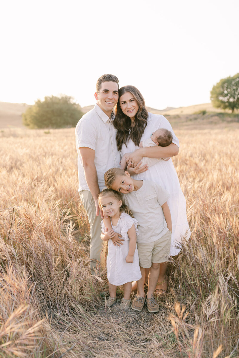 Orange County Family Photographer - a family of five standing in a dry grass field posing for a photo.