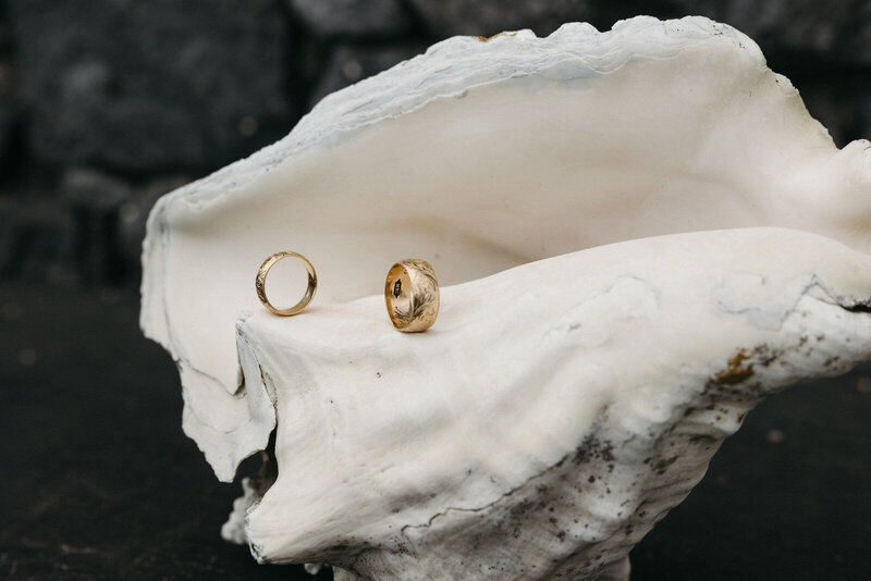 Wedding bands perfectly balanced on a conk shell sitting on volcanic rocks in Vila Franca do Campo, Azores Islands, Portugal, created by Andrea-Marie Photography