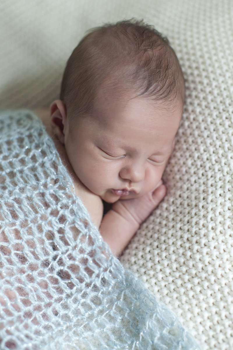 newborn sleeping under blanket