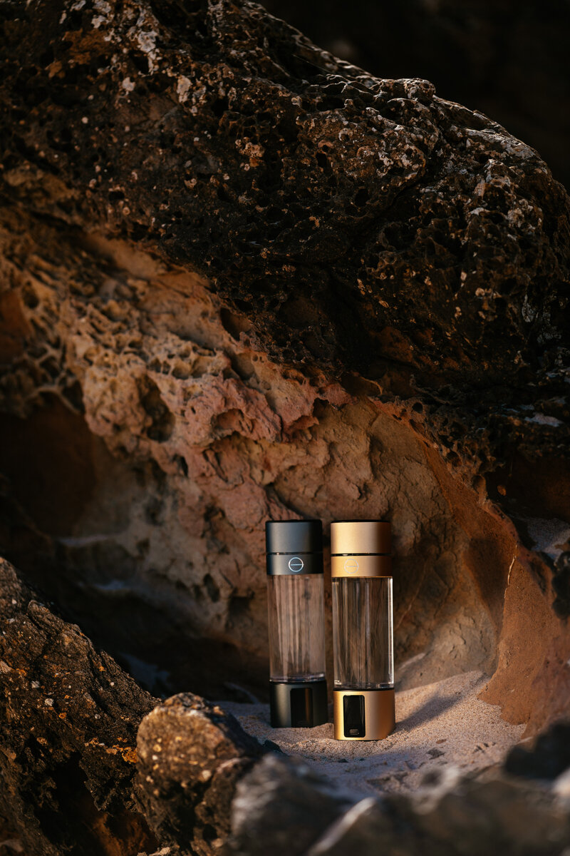 Two LumiVitae CellPower Hydrogen Water Bottles placed against a rocky background, highlighting the sleek design and advanced technology of the product.