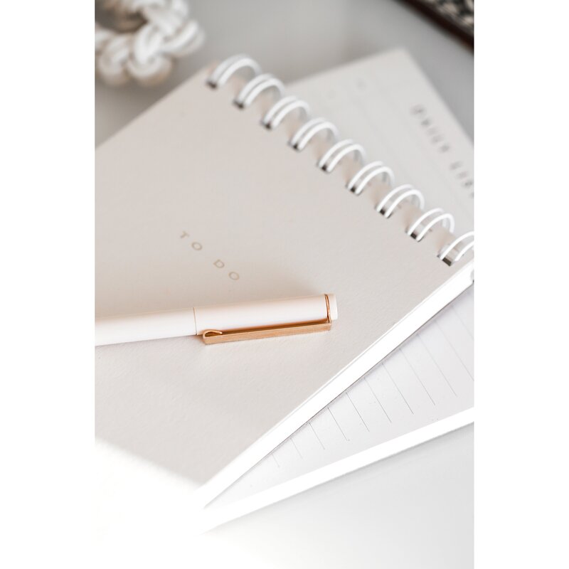 da notepad and gold pen to do list on a white desk