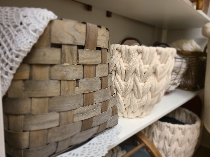 woven wooden and fabric baskets in neutral colors on white metal shelving