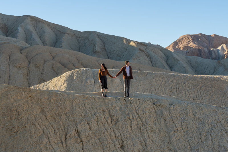 A couple holding hands and looking in opposite directions while in the desert