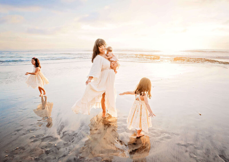 A mom dancing in the waves during her La Jolla family photography session